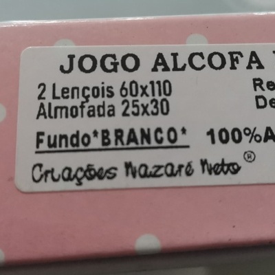 Etiqueta de embalagem rosa com bolinhas brancas a descrever jogo de roupa de cama para bebé.