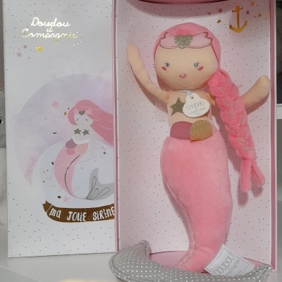 Boneca sereia de pelúcia rosa em caixa ilustrada