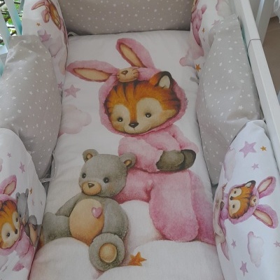 Berço com colchão e almofadas laterais acolchoadas com padrão de estrelas, imagem de urso de peluche e raposa com fato de coelho cor-de-rosa