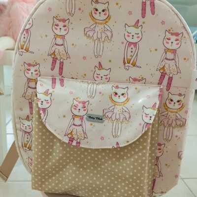 Mochila infantil rosa com padrão de gatinhas bailarinas e bolso bege com bolinhas brancas