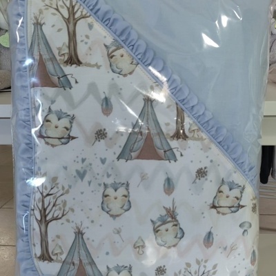 Manta para bebé azul claro e branca com padrão infantil de corujas e tendas embrulhada em plástico