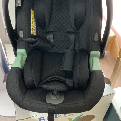 Cadeira auto para bebé preta com detalhes verdes e acolchoamento matelassê