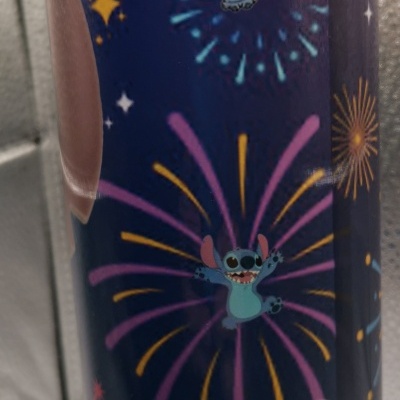 Lata cilíndrica azul com desenhos do personagem Stitch e fogos de artifício