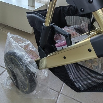 Carrinho de bebé dourado com roda protegida e bolsa inferior preta