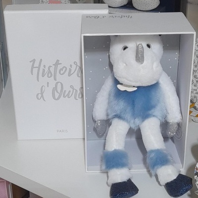 Peluche de elefante branco e azul numa caixa aberta com texto Histoire d'Ours