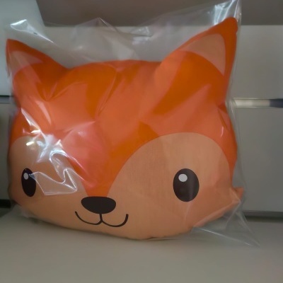 Almofada de pelúcia com rosto de raposa embalada em saco plástico