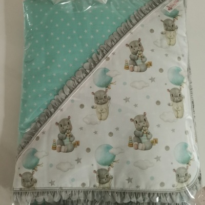 Manta dupla face azul e branca com padrão de hipopótamos e estrelas embalada em plástico