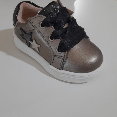 Sapato desportivo infantil cinza metálico com estrelas e atacadores pretos sobre mesa branca