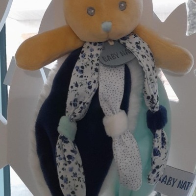 Brinquedo suave de coelho azul e amarelo com padrões florais e etiquetas BABY NAT