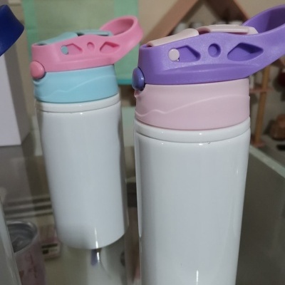 Duas garrafas térmicas brancas com tampas coloridas em azul claro e rosa, e lilás e rosa, numa mesa reflexiva.