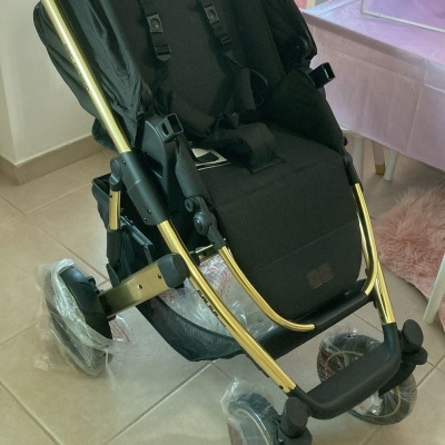 Carrinho de bebé preto com estrutura dourada em ambiente interior