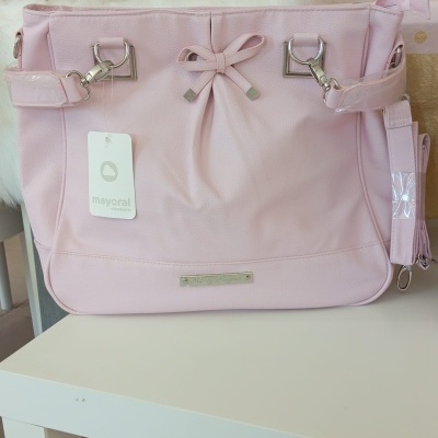 Mala rosa claro com laço e etiqueta mayoral sobre mesa branca