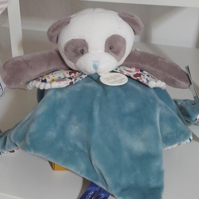 Pelúcia panda azul e cinza para bebé numa prateleira branca