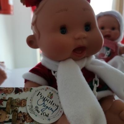 Boneca bebé com roupas vermelhas e brancas e laços vermelhos