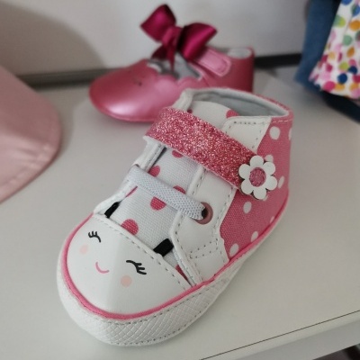 Tênis infantil branco e cor-de-rosa com bolinhas e fecho rosa glitter numa prateleira