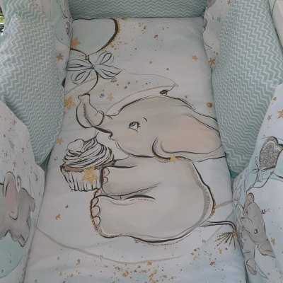 Berço de bebé com roupa de cama azul claro com elefante e cupcake
