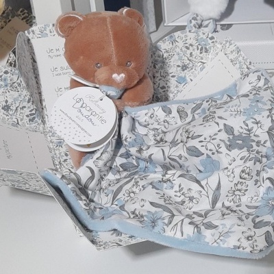 Ursinho de peluche castanho claro com manta floral azul e caixa decorada com padrão floral