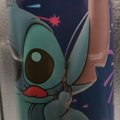 Copo metálico com tampa e decoração da personagem Stitch em fundo azul com estrelas e fogos-de-artifício