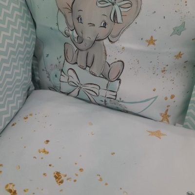 Almofada com desenho de elefante e balões, com padrão de estrelas douradas e tecido chevron verde e branco