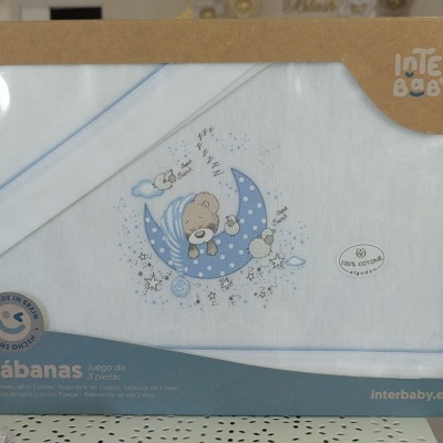 Conjunto de sábanas para bebé branco com bordado de ursinho a dormir numa lua azul embalado em cartão