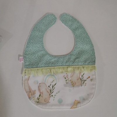 Babete de bebé verde com pontos brancos e coelhos em tecido branco com franjas amarelas