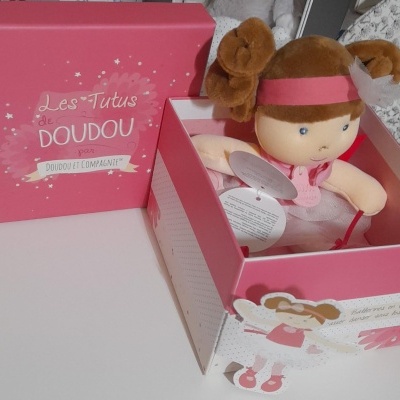 Caixa rosa com boneca de pelúcia vestida de rosa e texto Les Tutus des DOUDOU