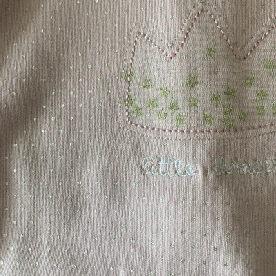 Tecido rosa claro com pontos verdes, bordado de coroa e texto little dancer.