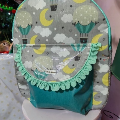 Mochila infantil com padrão de balões, luas e nuvens, bolso verde água com franja