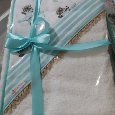 Toalha de banho com capuz e padrão de guaxinins, embalada com fita azul.