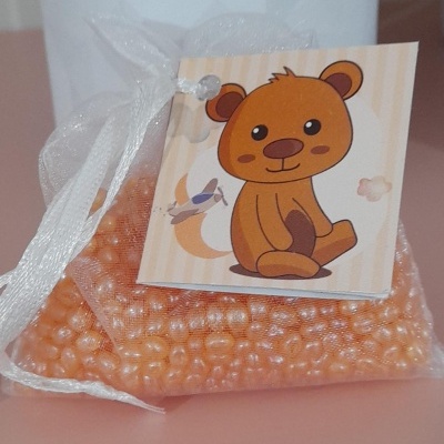 Saco transparente com pérolas laranja e etiqueta com desenho de urso