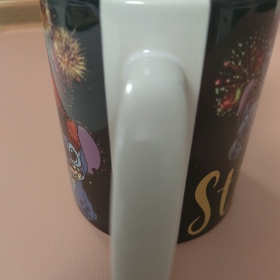 Caneca preta com estampas de fogos de artifício e personagens de desenho animado.