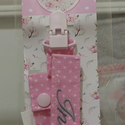 Tiraleite ou prendedor para chupeta cor de rosa com padrões de estrelas brancas em embalagem transparente