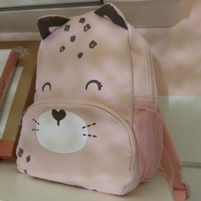 Mochila infantil rosa com rosto de gato desenhado e bolso frontal, em superfície branca