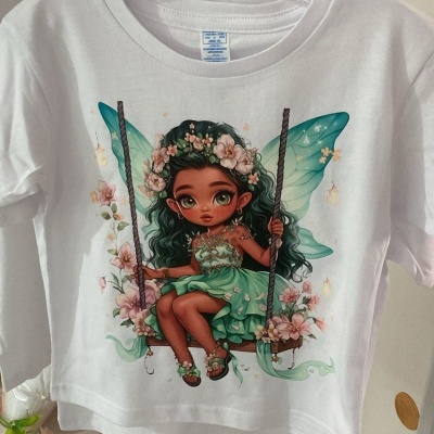 T-shirt branca com estampa colorida de fada com asas azuis e flores.