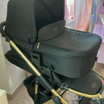 Carrinho de bebé preto com estrutura dourada