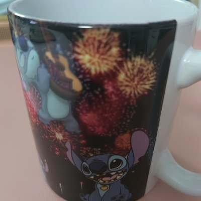 Caneca preta com personagens Stitch e fogos de artifício coloridos