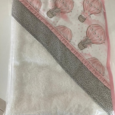 Toalha de bebé branca com capuz decorado com balões cor de rosa e padrão de bolinhas cinza.