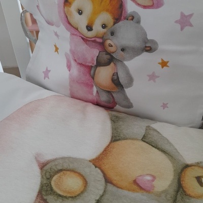 Conjunto de almofada e edredão com desenhos de animais fofos em tons pastel.