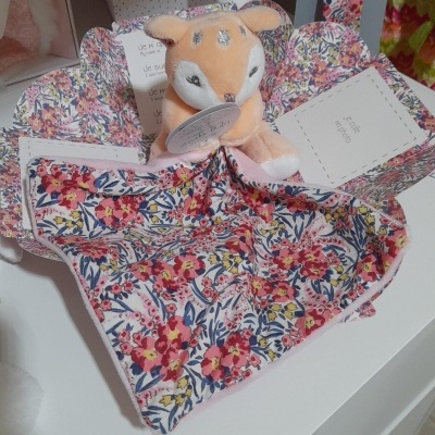 Pelúcia de veado cor-de-rosa sobre tecido floral dentro de caixa florida