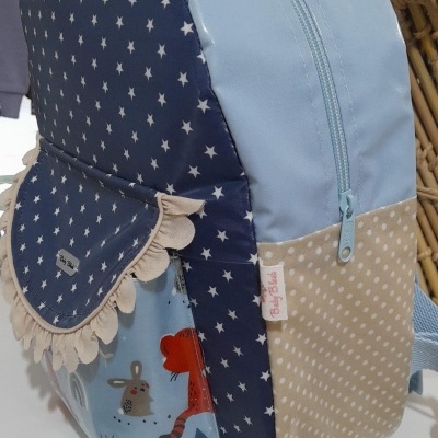 Mochila infantil com padrão de estrelas azuis, bolinhas bege e desenho de animais
