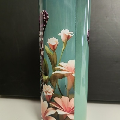 Copo metálico decorado com flores rosas em fundo azul esverdeado