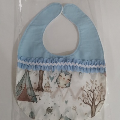 Babete de bebé azul e branco com padrões de árvores, tenda e corujas
