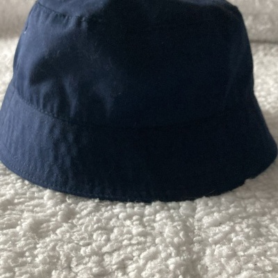 Chapéu tipo bucket azul-escuro sobre superfície branca felpuda