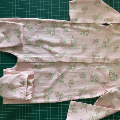 Pijama de bebé cor-de-rosa com padrão de coelhinhos verdes e rosas
