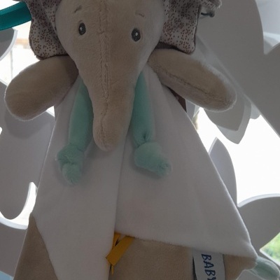 doudou elefante de peluche bege branco com detalhes azul claro amarelo e etiqueta BABY NAT