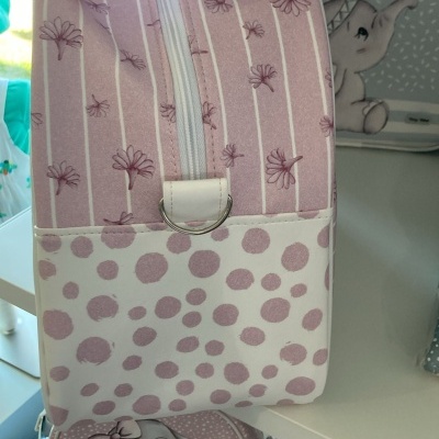 Mala e bolsa rosa com padrão de bolas e flores e toalhete rosa com elefante desenhado