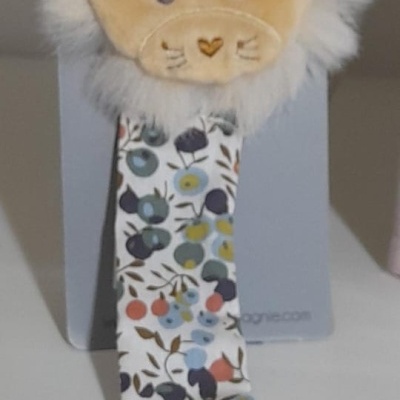 Prendedor de chucha com cabeça de leão em tecido felpudo e fita floral colorida