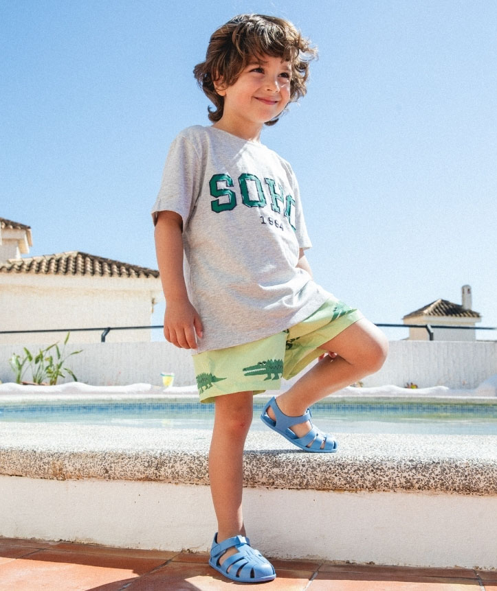 IGOR Barefoot Nemo Solid - Azul Criança com roupa casual colorida junto a uma piscina num dia ensolarado.