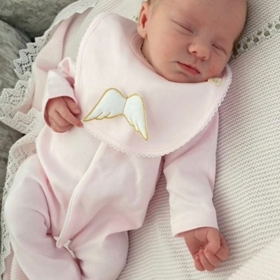 bebé dormindo com fato de treino rosa e babete com asas bordadas a dourado