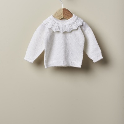 Camisola branca de malha para criança com gola frisada num cabide de madeira